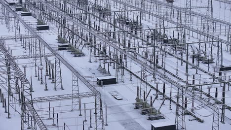 Snow-and-ice-covered-high-power-transformation-station,-drone-truck-shot