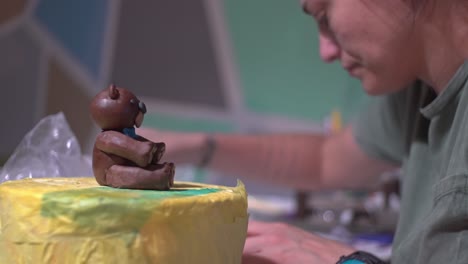 Side-view-of-caucasian-woman-decorating-a-cake-with-sugar-paste-fondant-bear-at-home