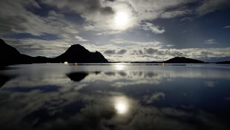 Escena-Nocturna-Con-La-Luna-Llena-Brillando-Detrás-De-Las-Nubes-Flotantes-Con-Sus-Reflejos-En-El-Tranquilo-Fiordo