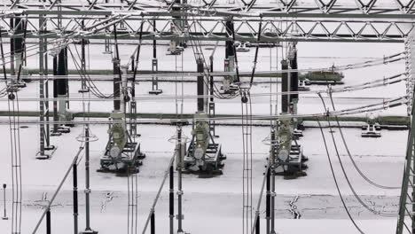 Cable-and-power-line-close-up-in-wintery-transformation-power-station,-drone-truck-shot