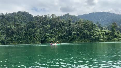 Two-individuals-paddle-in-harmony-on-Khao-Sok-Lake-in-Thailand