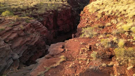 Woman-admiring-panorama-on-edge-of-Joffre-deep-gorge-during-hiking-adventure,-Western-Australia-desert
