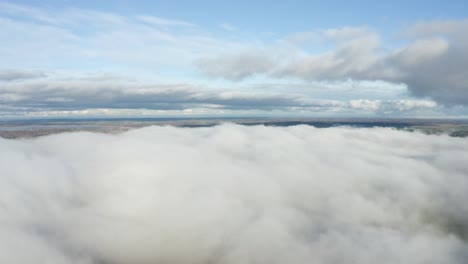 Slow-calm-aerial-between-white-fluffy-cloud-bed-sky-view-on-land-horizon