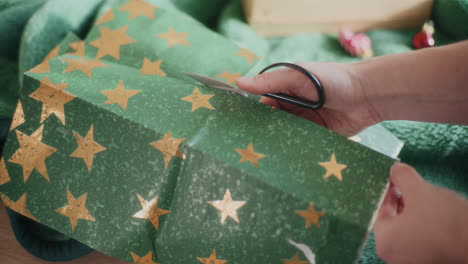 Hands-cutting-star-shaped-green-wrapping-paper-during-Christmas-at-home
