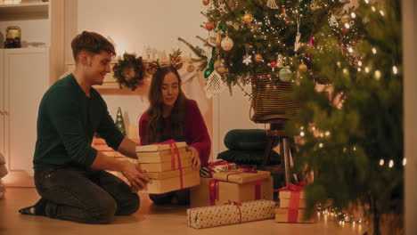 Couple-arranging-gift-boxes-by-Christmas-tree