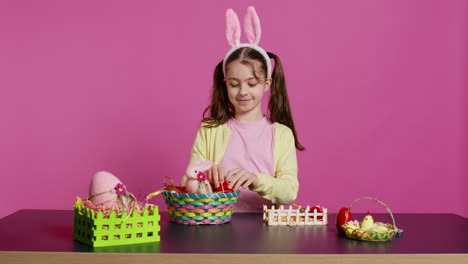 Cute-smiling-toddler-decorating-a-basket-with-painted-easter-eggs