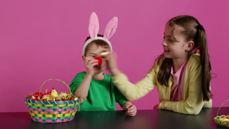 Sweet-children-knocking-eggs-together-for-easter-tradition-in-studio,