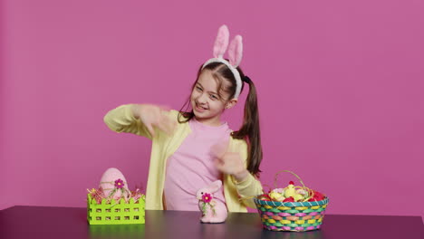 Smiling-confident-toddler-placing-bunny-ears-on-her-head-and-waving