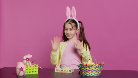 Energetic-young-girl-with-adorable-bunny-ears-waving-in-studio