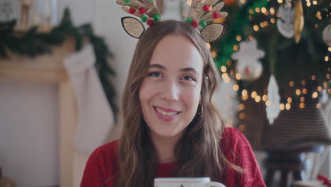 Beautiful-woman-smiling-while-holding-fresh-coffee-cup-during-Christmas
