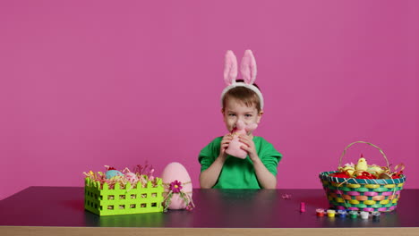 Adorable-little-child-playing-with-a-stuffed-rabbit-and-a-pink-egg-at-table