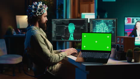Engineer-with-EEG-headset-on-merging-with-AI,-green-screen-laptop