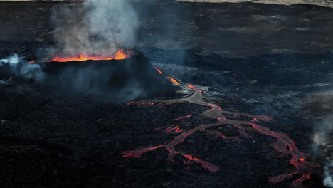 Erupting-volcano,-lava-pouring-out-into-a-devastated-surrounding,-drone-shot