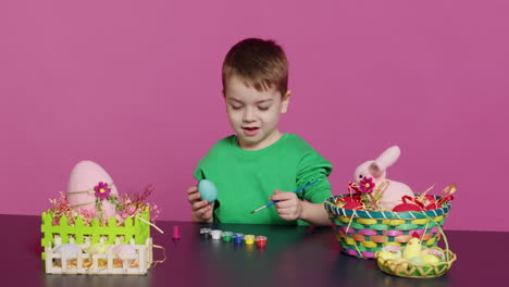 Joyful-small-kid-painting-eggs-for-easter-holiday-festivity-in-studio