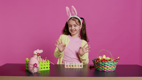 Joyful-schoolgirl-with-bunny-ears-waving-hello-in-front-of-camera