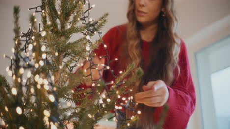Frau-Schmückt-Weihnachtsbaum-Mit-Leuchtenden-Lichtern
