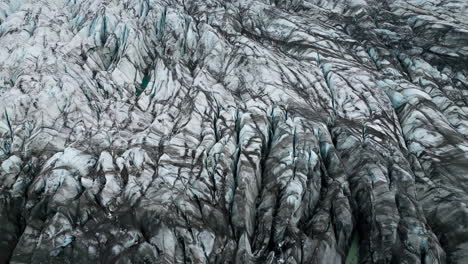Ice-terraces-of-glacier-tongue,-rough-surface-with-crack-pattern,-aerial-view