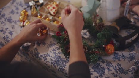 Man-tying-baubles-on-wreath-at-home