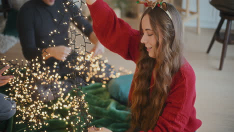 Woman-sorting-tangled-glowing-lights-with-friends