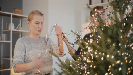 Freunde-Schmücken-Weihnachtsbaum-Mit-Beleuchteten-Lichtern