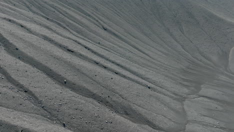 Dark-sand,-black-volcanic-sand-waves-texture,-aerial-shot