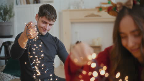 Man-sorting-tangled-illuminated-lights-with-friends