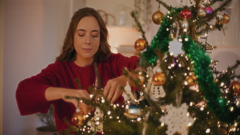 Woman-tying-Christmas-ornaments-on-tree
