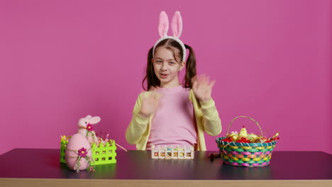 Energetic-young-girl-with-adorable-bunny-ears-waving-in-studio