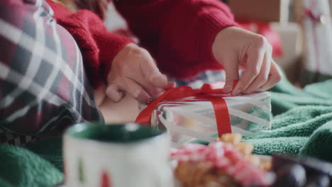 Closeup-of-woman-making-ribbon-bow-on-wrapped-Christmas-gift