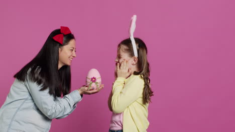 Schöne-Mutter-überrascht-Ihre-Tochter-Zu-Ostern-Mit-Einem-Süßen-Rosa-Ei