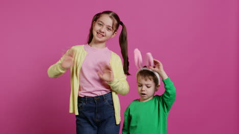 Joyful-little-kids-waving-in-front-of-camera-during-easter-holiday