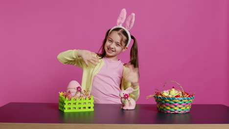 Smiling-confident-toddler-placing-bunny-ears-on-her-head-and-waving