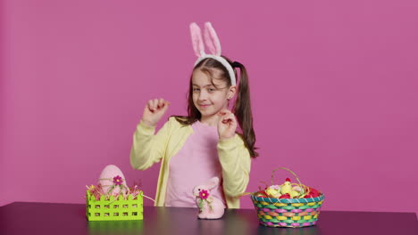 Cheery-innocent-child-showing-peace-sign-in-studio-and-wearing-bunny-ears