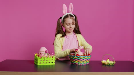 Excited-young-girl-arranging-painted-eggs-in-a-basket-to-prepare-for-easter