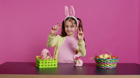 Cheery-innocent-child-showing-peace-sign-in-studio-and-wearing-bunny-ears