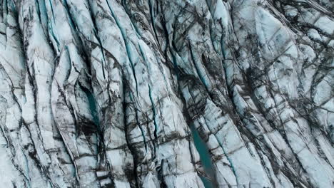 Glacier-tongue,-ice-with-volcanic-ash-layers,-and-turquoise-water,-aerial-shot