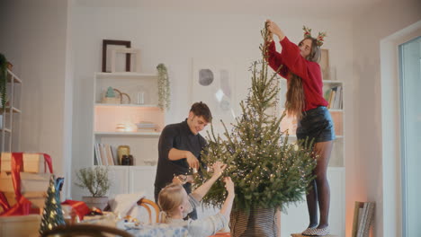 Männer-Und-Frauen-Schmücken-Den-Weihnachtsbaum-Mit-Lichtern