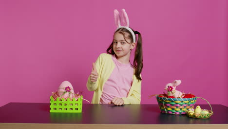Happy-schoolgirl-with-bunny-ears-showing-thumbs-up-sign