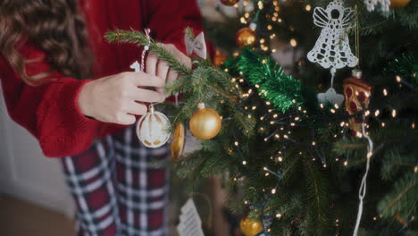 Woman-hanging-bauble-on-Christmas-tree-at-home