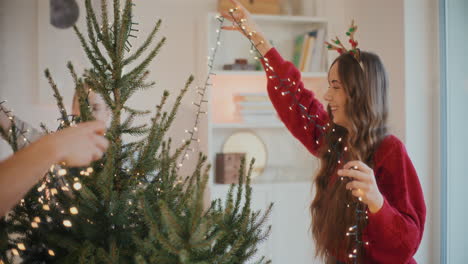 Young-friends-adjusting-lights-on-Christmas-tree