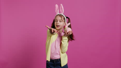 Jolly-schoolgirl-holding-a-cute-rabbit-toy-and-blowing-kisses-in-studio