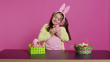 Cheerful-smiling-girl-hugging-her-stuffed-rabbit-toy-and-egg