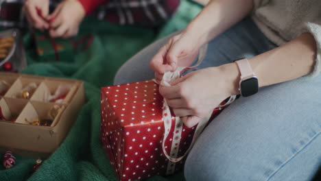 Woman-tying-ribbon-on-wrapped-Christmas-gift-at-home