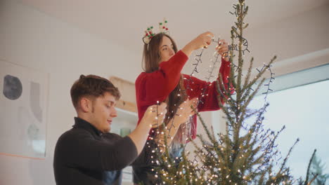 Couple-decorating-Xmas-tree-with-glowing-lights