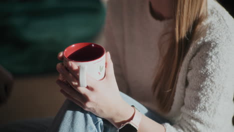 Woman-holding-coffee-cup-at-bright-home-during-Christmas
