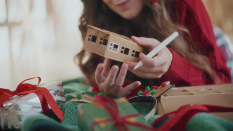 Cropped-woman-coloring-cardboard-house-ornament-during-Christmas