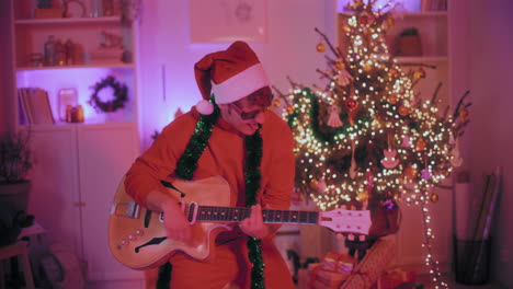 Hombre-Alegre-Tocando-La-Guitarra-En-Casa-Durante-La-Navidad