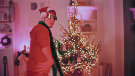 Man-with-green-tinsel-on-shoulder-dancing-at-home-during-Christmas
