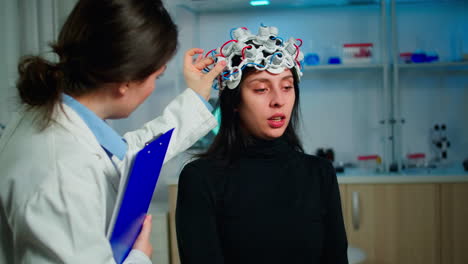 Patient-with-eeg-headset-discussing-with-medical-researcher-during-examination