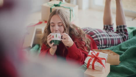 Schöne-Frau-Trinkt-Kaffee,-Während-Sie-Während-Weihnachten-Auf-Dem-Boden-Liegt